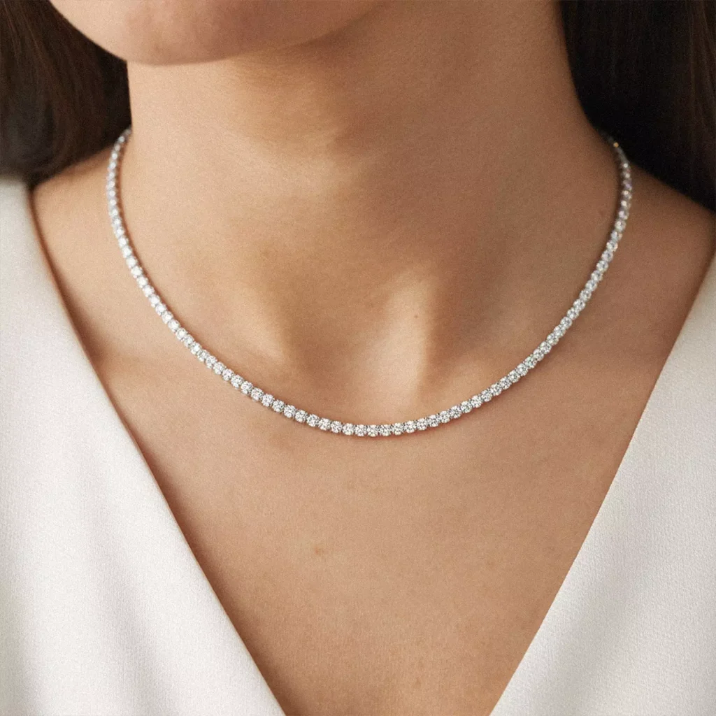 A close-up of a woman's neckline to highlight the diamond tennis necklace 
